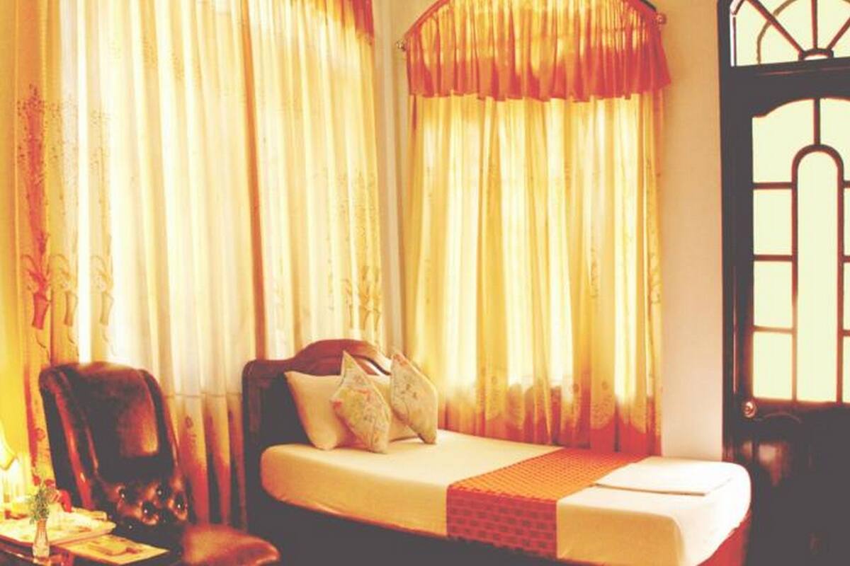 Una habitación con una cama, una silla y una mesa con una lámpara.