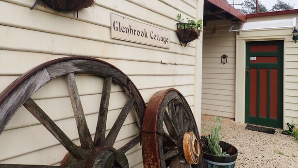A building with a sign reading "Glenbrook Cottage" and two large wooden wheels attached to the wall. - Glenbrook House and Cottage (Penguin)