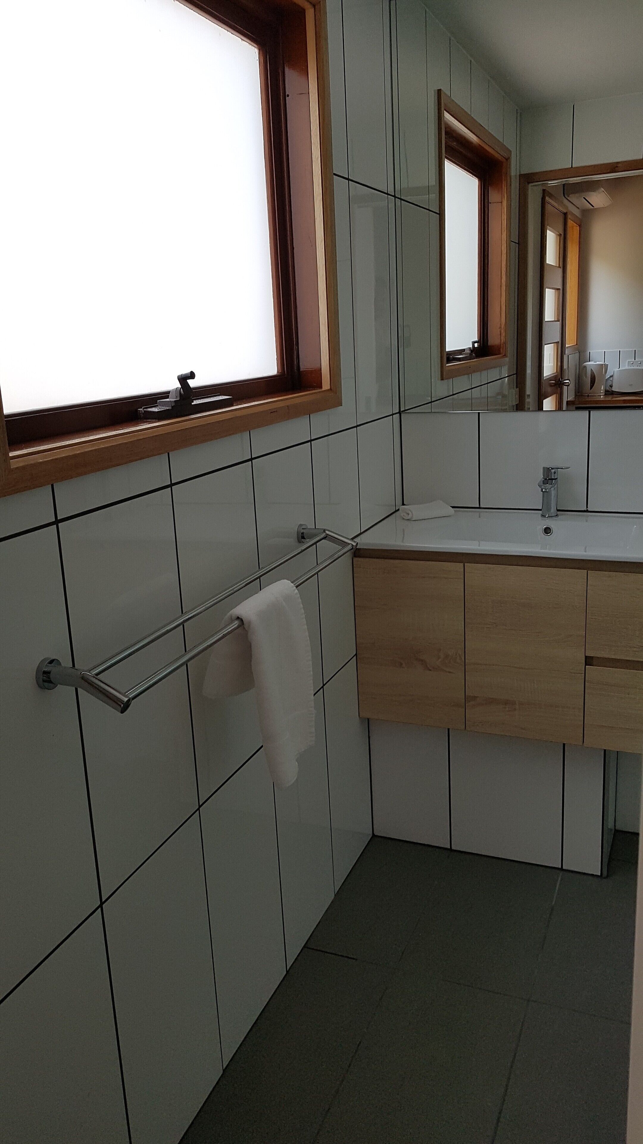 Een moderne badkamer met een grote spiegel, een handdoekhouder en een wastafel.