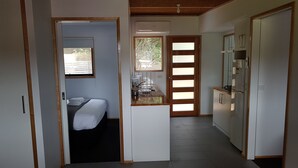 Una habitación de hotel compacta con cama, una kitchenette pequeña y vistas por la ventana.