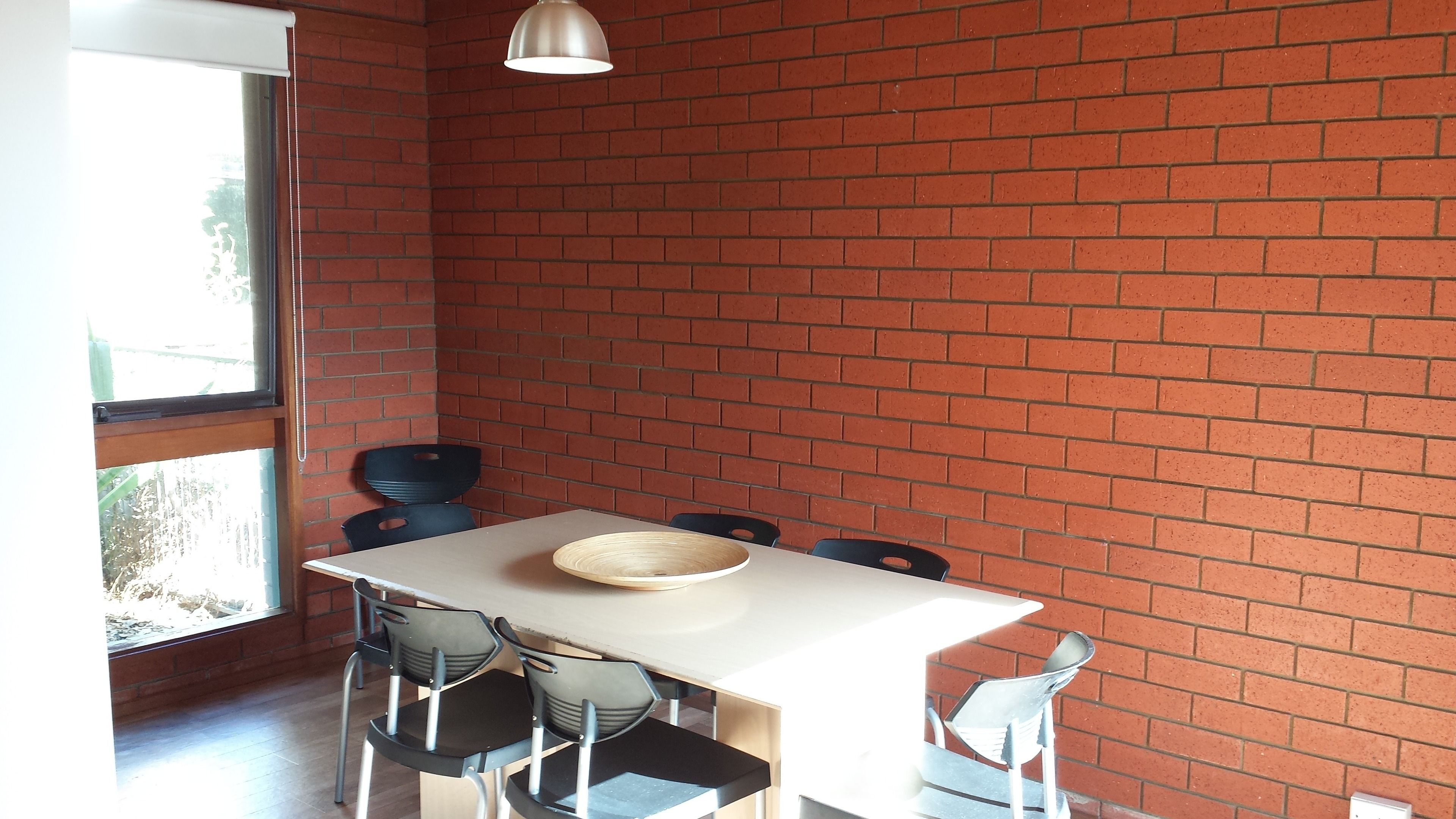 A dining area with a brick wall, a white table, and four chairs.