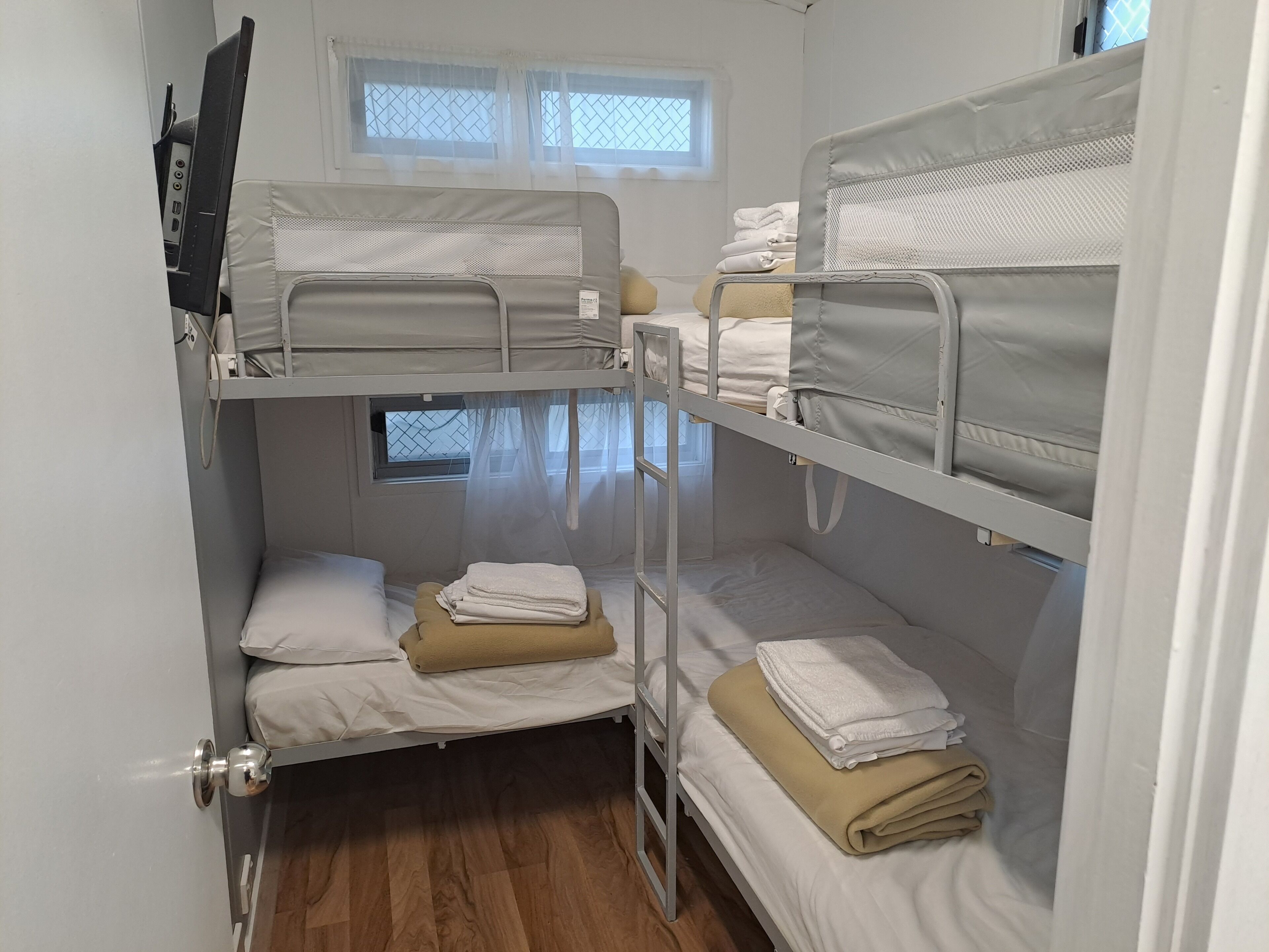 A bunk bed room with two beds, a window, and a door.