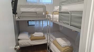 A bunk bed room with two beds, a window, and a door.