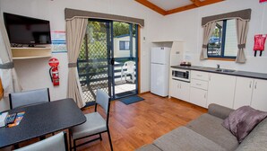 Una kitchenette compacta con microondas, fregadero y refrigerador. Hay un comedor con mesa y sillas, y un sofá en la sala.