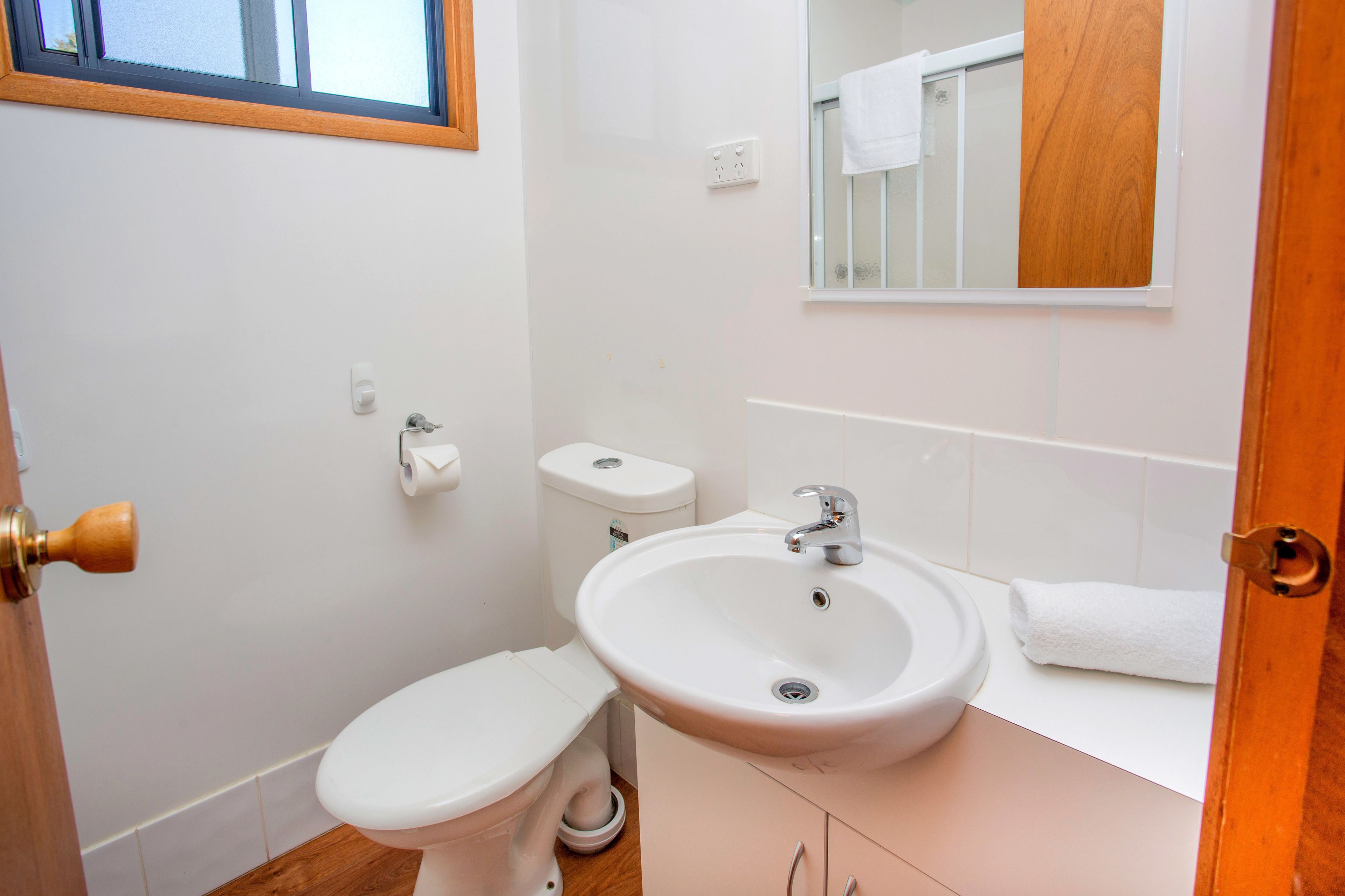 Een kleine badkamer met toilet, wastafel en een spiegel boven de wastafel.