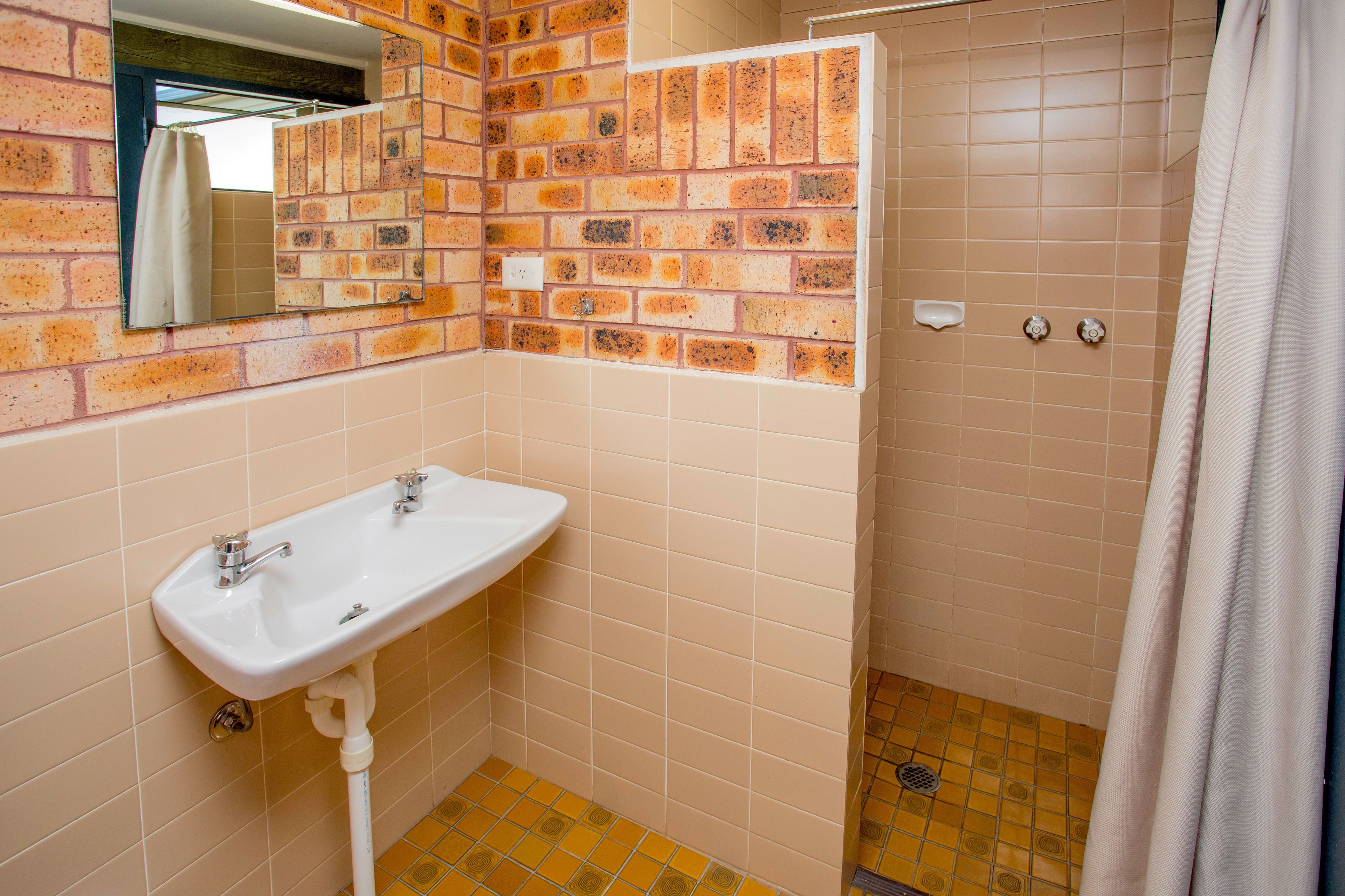 A bathroom with a white sink, a mirror, and a shower area.