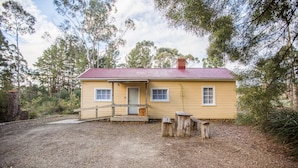A yellow house with a red roof, surrounded by trees and a gravel driveway. - Rosedale Cottages (Taranna)