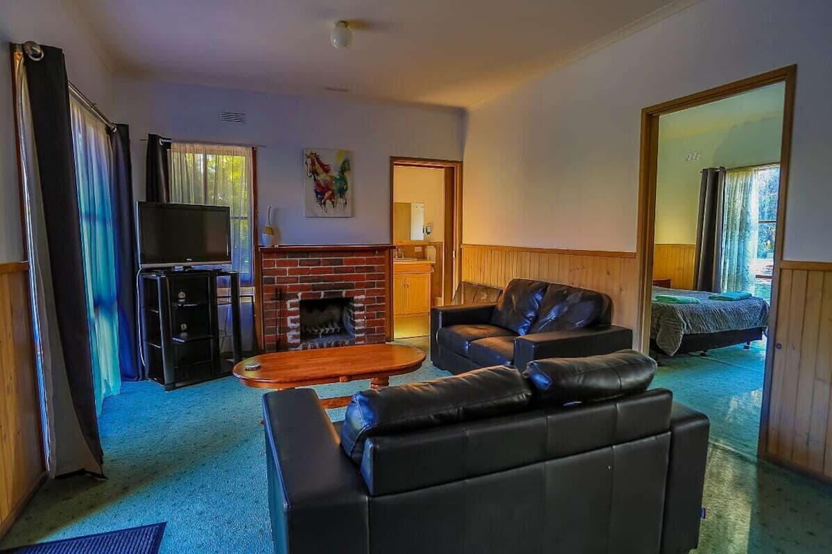 A living room with a fireplace, leather sofas, a TV, and a large mirror.