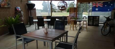Un patio couvert avec une table et des chaises, un objet décoratif suspendu et un drapeau australien.