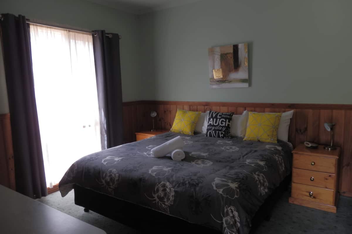 A bedroom with a bed, a nightstand, a lamp, and a painting on the wall.