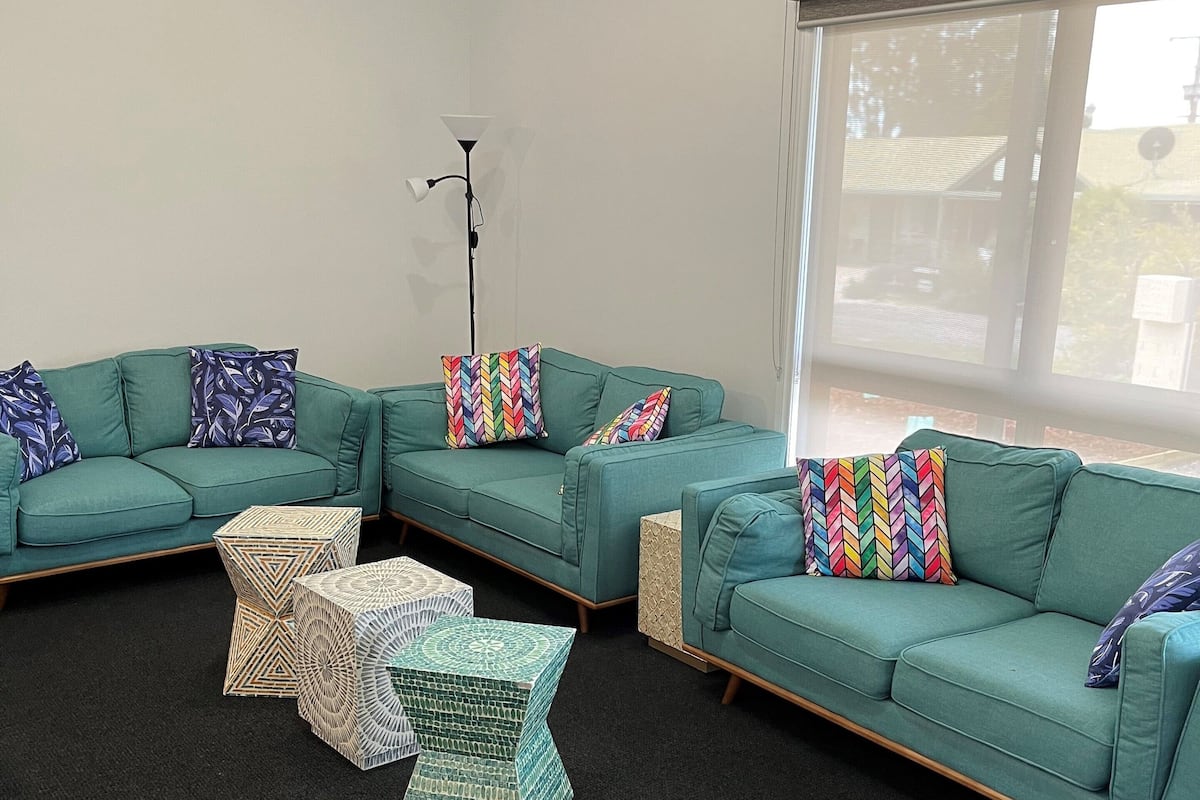 A modern living room with a sectional sofa set, patterned throw pillows, and a floor lamp.