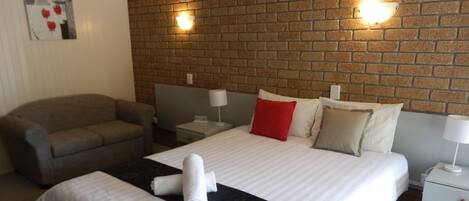 Una habitación de hotel con una cama, un sofá y una pared de ladrillo.