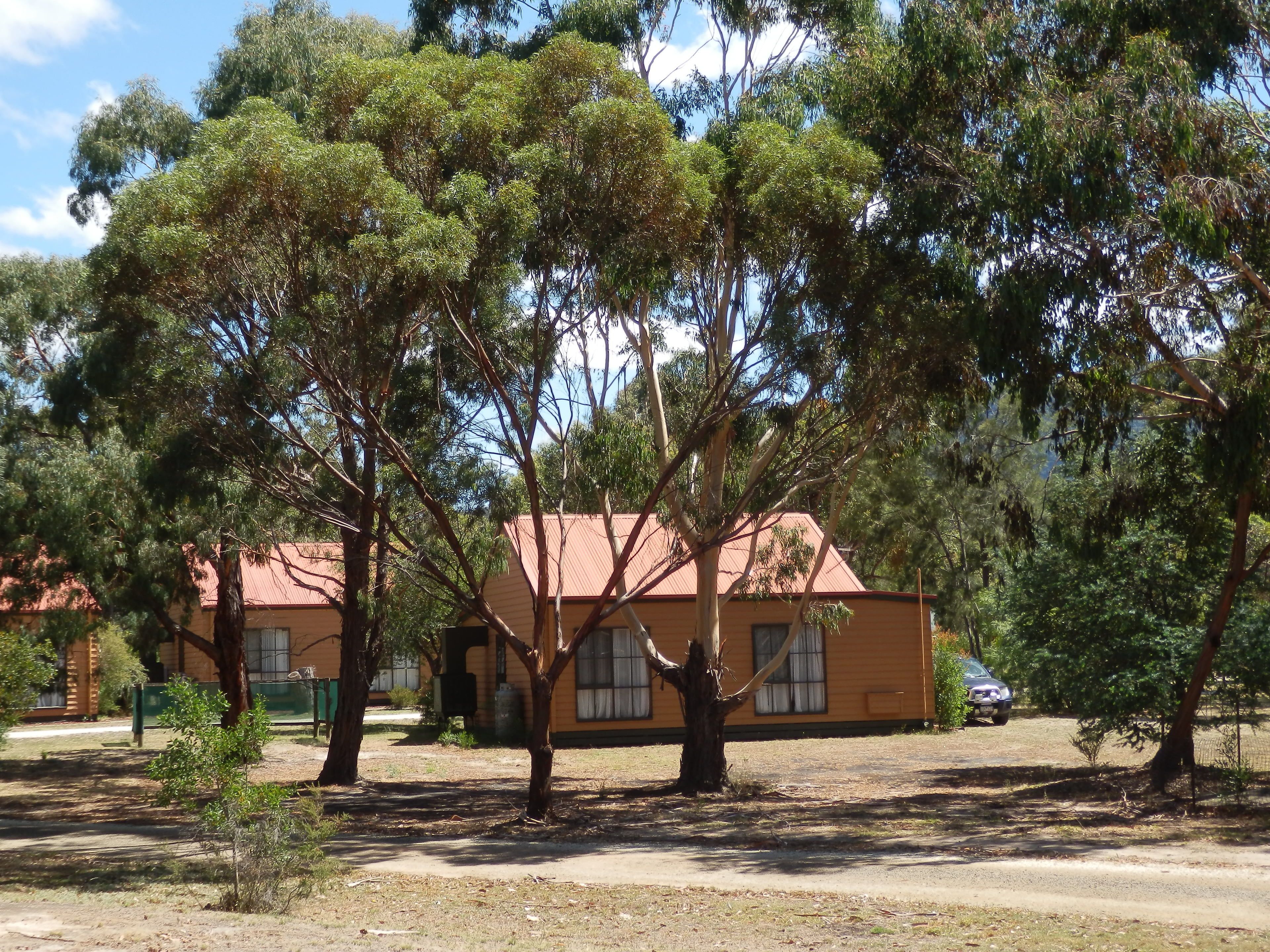 A yellow building with a red roof, surrounded by trees.