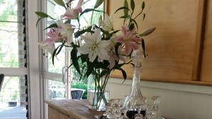 A wooden console table with a glass vase of flowers and wine glasses. - Elfin Hill Country Accommodation (Pokolbin)