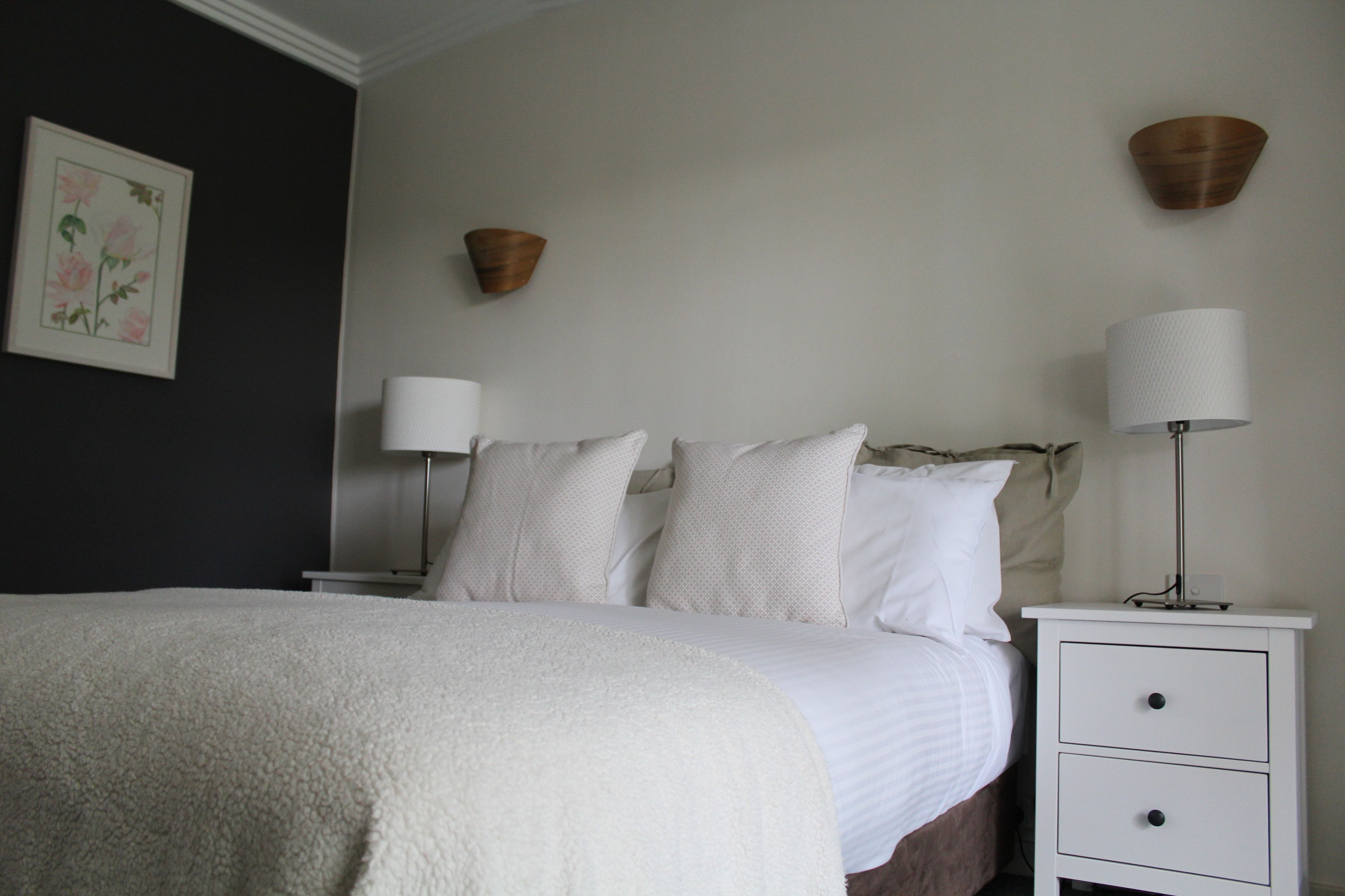 Un dormitorio con una cama, dos mesitas de noche y una lámpara de pared.
