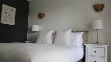 Un dormitorio con una cama, dos mesitas de noche y una lámpara de pared.