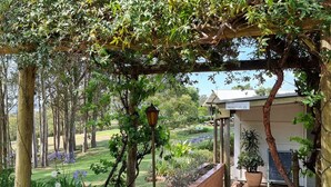 A garden with a pergola, a reception area, and a pathway leading to a building. - Elfin Hill Country Accommodation (Pokolbin)