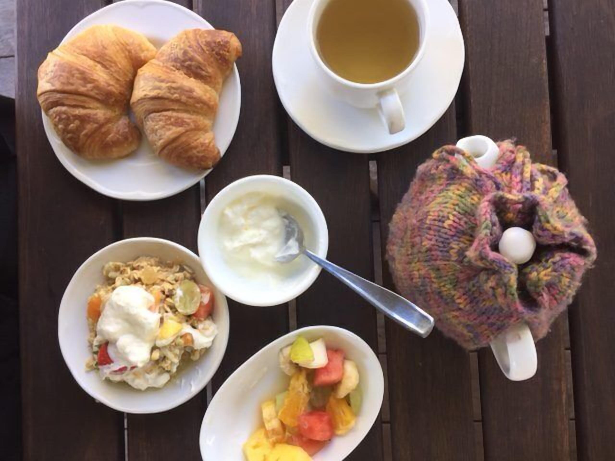 Esmorzar amb croissants, una tassa de te, iogurt amb fruita i un objecte de punt.