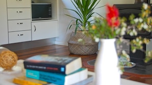 Ein modernes Wohnzimmer mit Mikrowelle, Zimmerpflanze und Bücherregal.