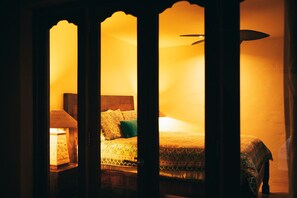 Una habitación cálidamente iluminada con una cama, una mesita de noche y una lámpara.
