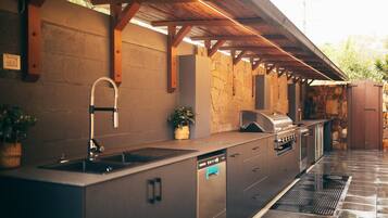 An outdoor kitchen with a built-in sink, a grill, and a dishwasher.