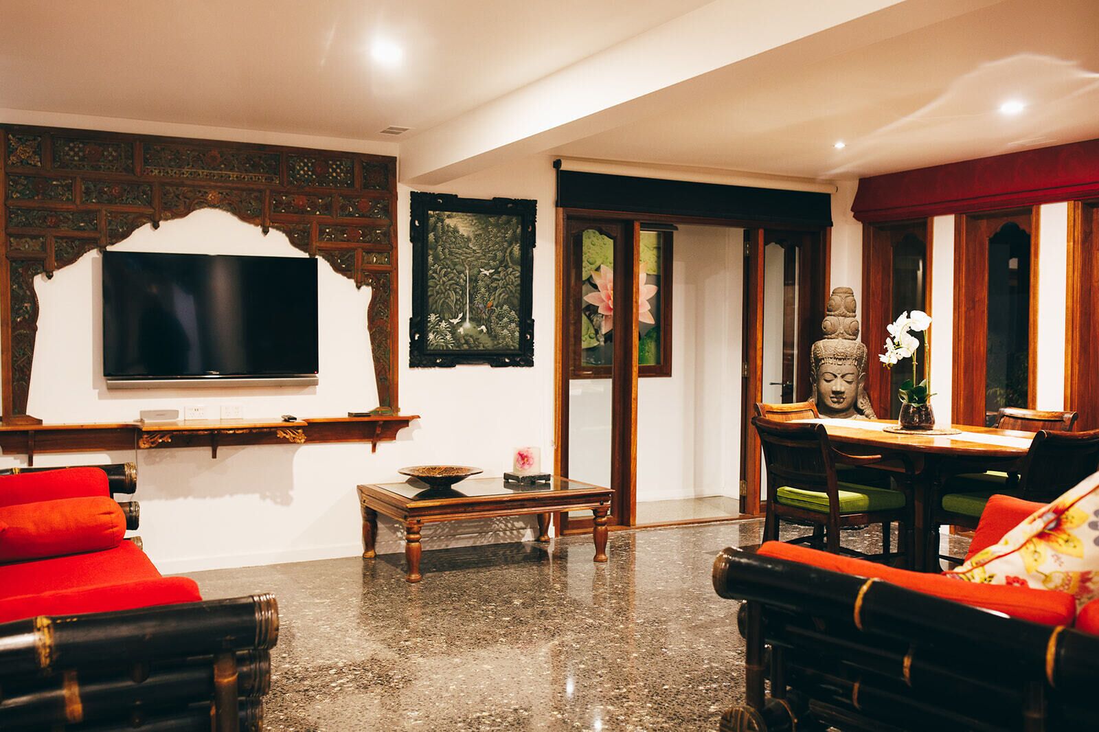 A traditional room with a television, a Buddha statue, and a dining area with a table and chairs.