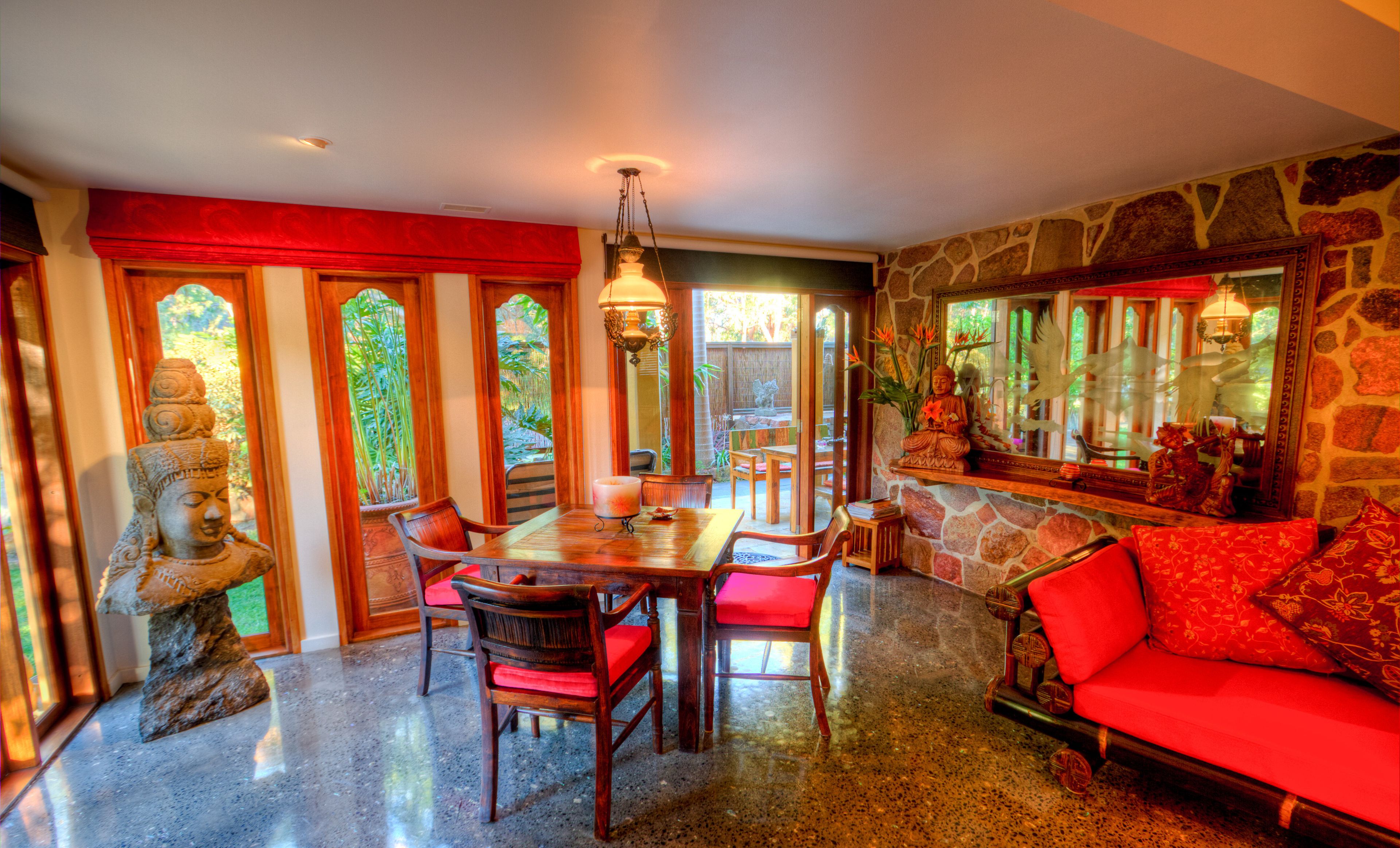 A dining area with a wooden table, red chairs, and a Buddha statue.