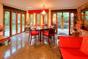Una habitación amplia con comedor, un sofá rojo y una estatua de Buda.