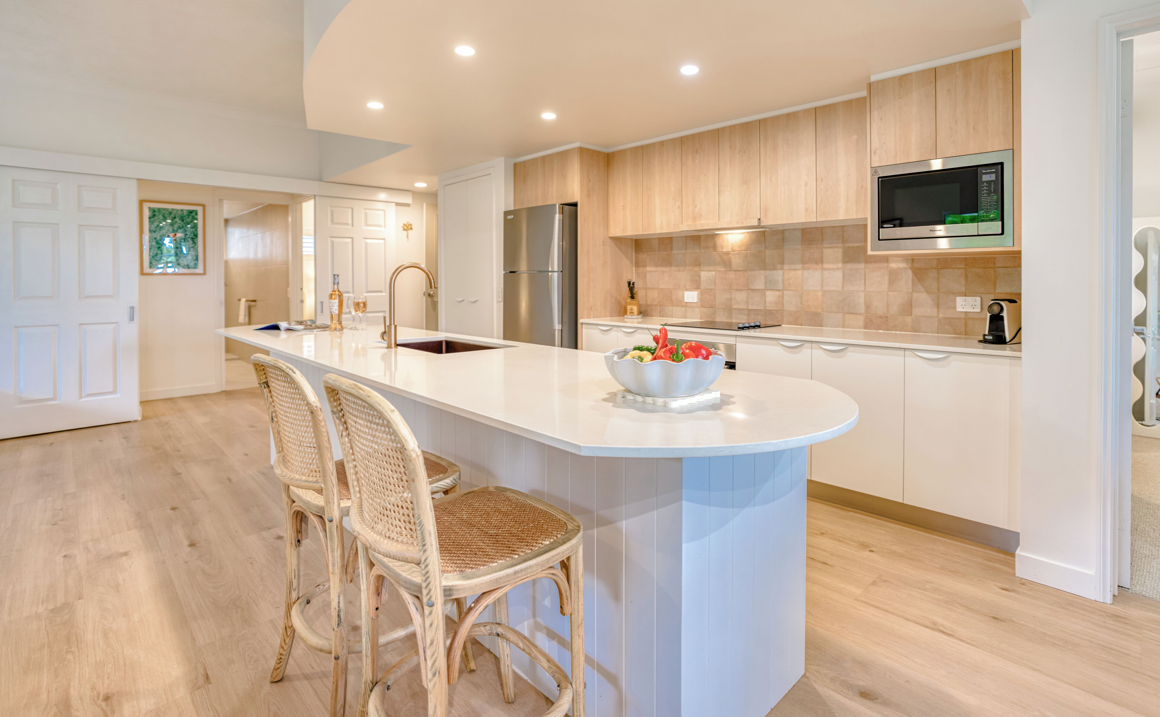 A modern kitchen with a central island, wooden cabinets, stainless steel appliances, and a built-in microwave.