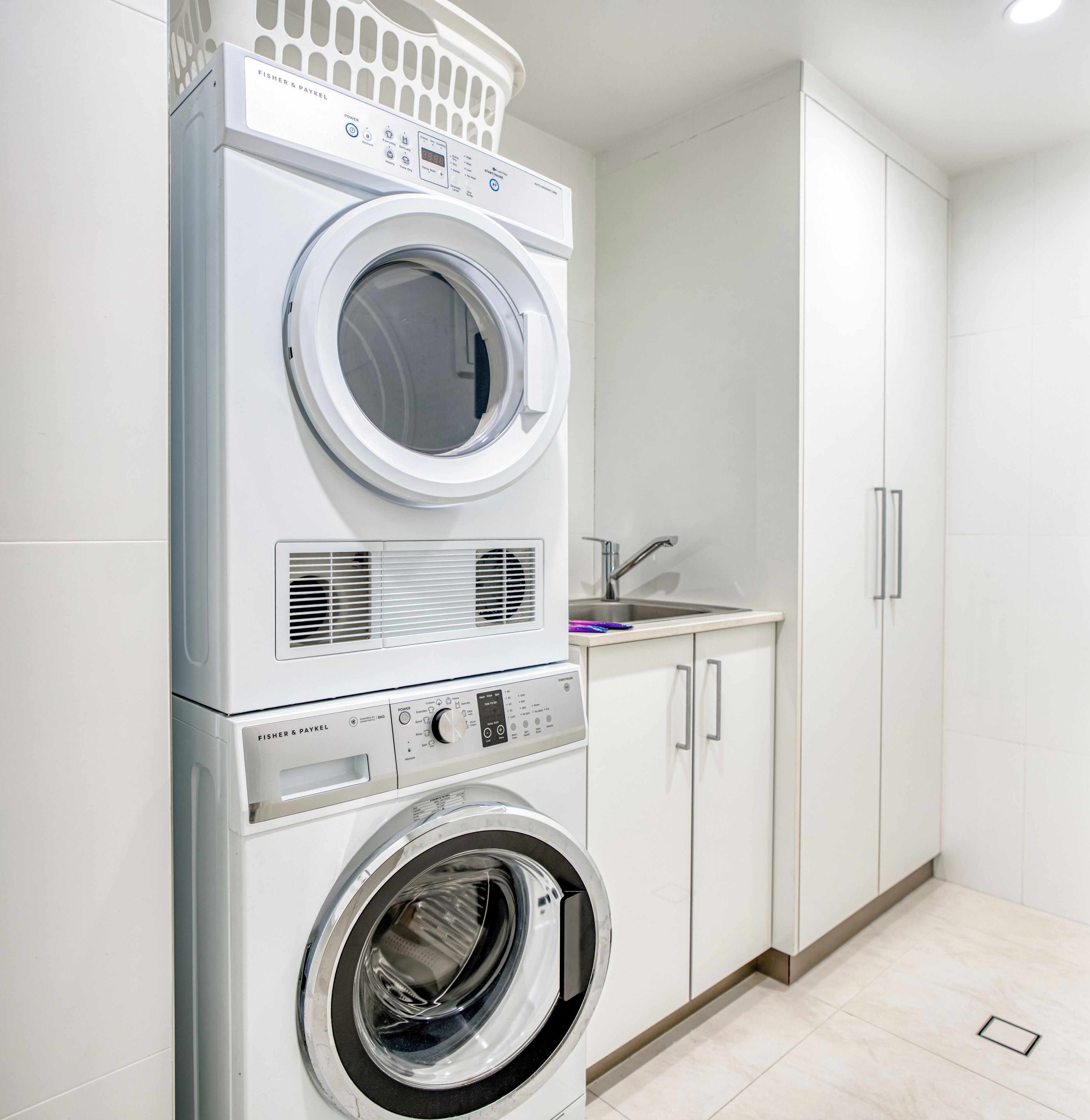 Un área de lavandería con lavadoras apiladas y un lavabo.