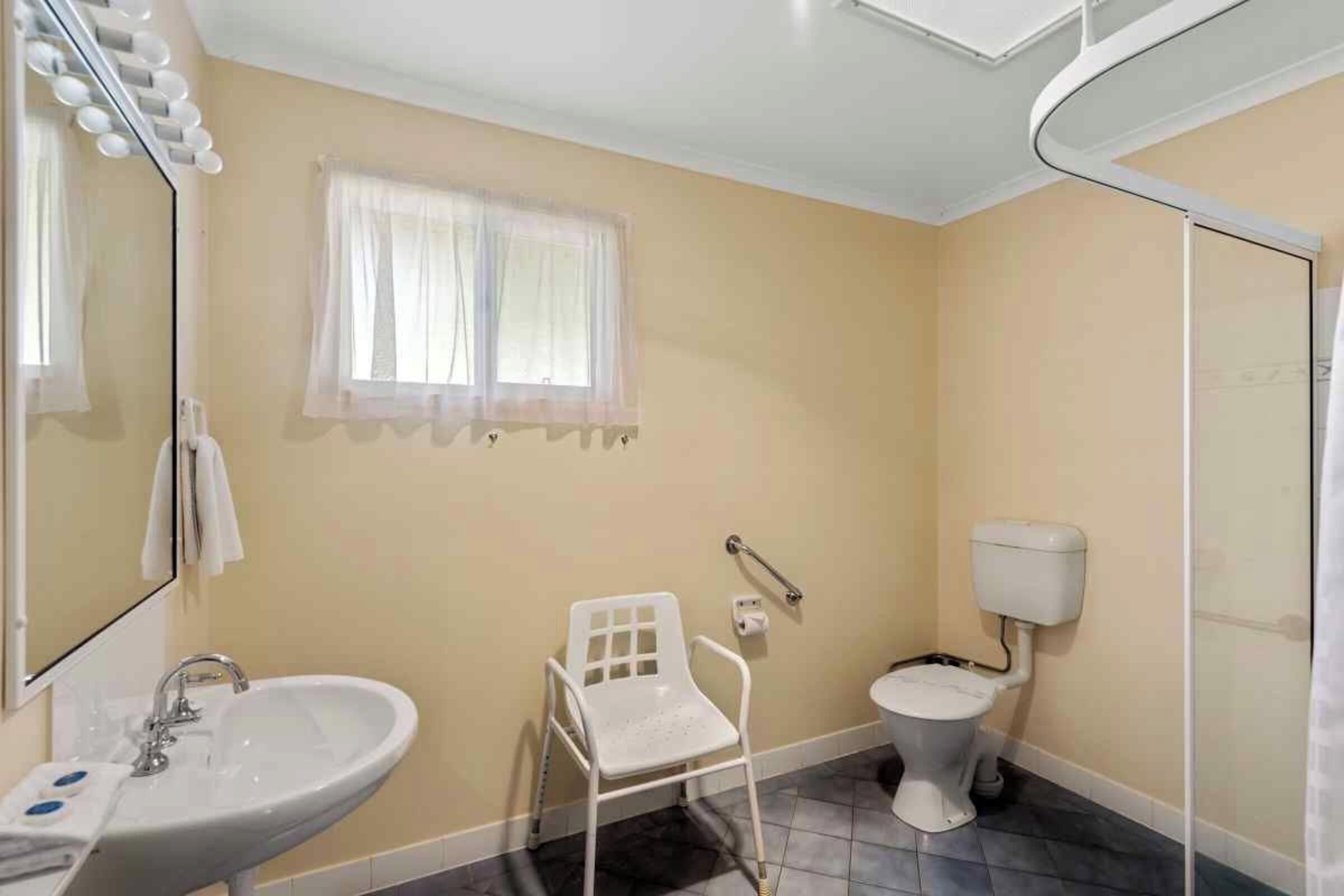 Un baño con lavamanos, inodoro y una silla.