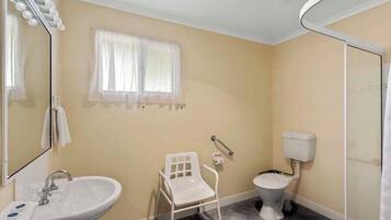 Un baño con lavamanos, inodoro y una silla.