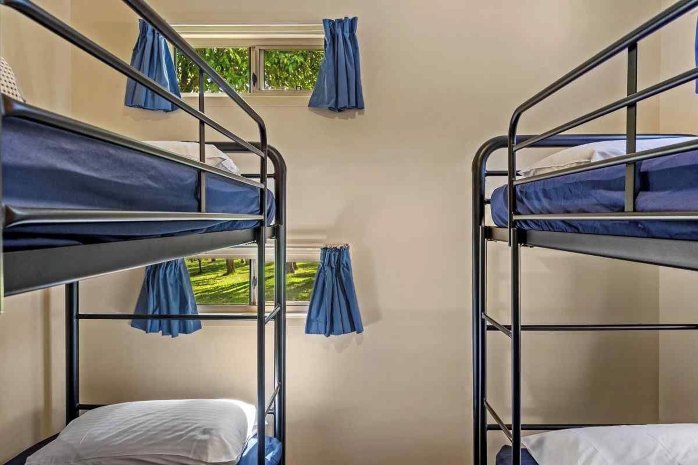 A bunk bed room with two beds, each with a blue curtain.