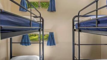 Habitación con literas dobles, cada una con una cortina azul.
