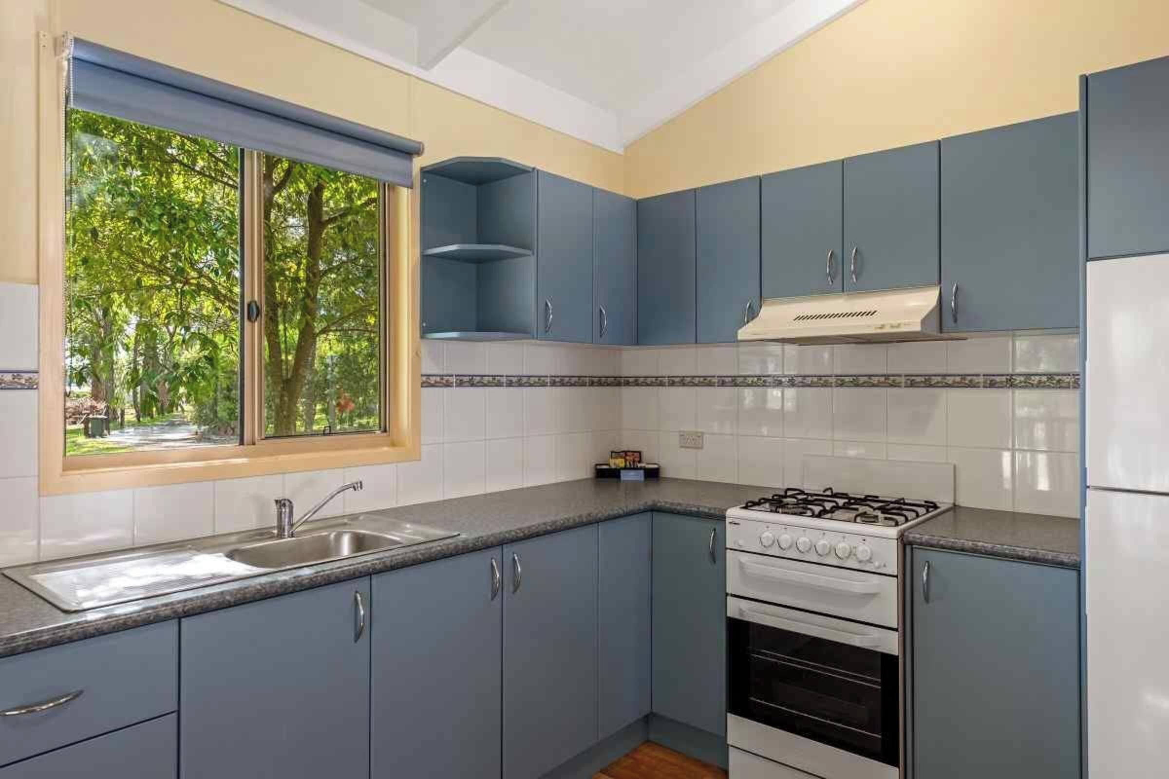 A kitchen with blue cabinets, a gas stove, and a built-in oven.