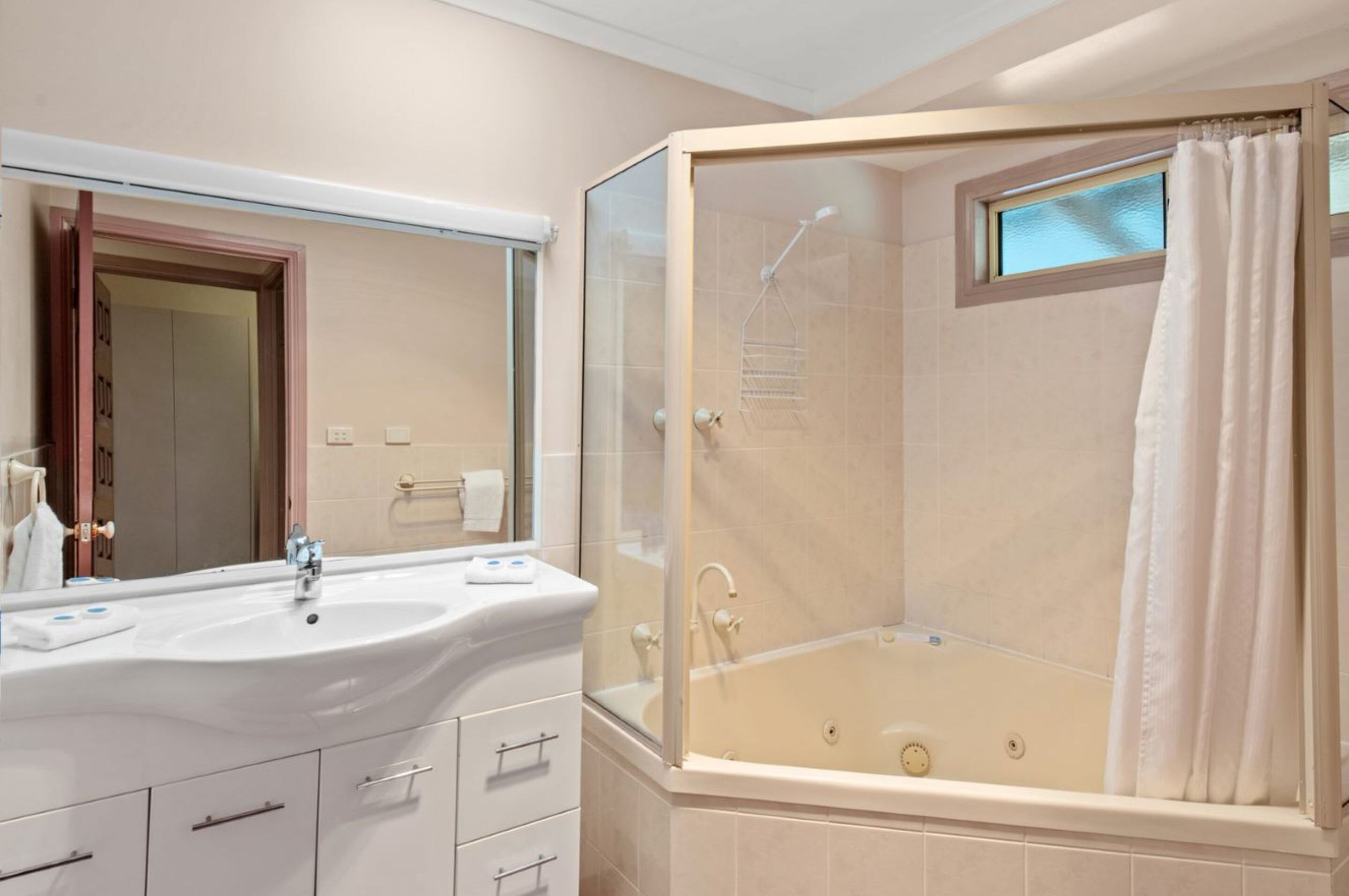 A bathroom with a white sink, mirror, and a glass-enclosed shower area.