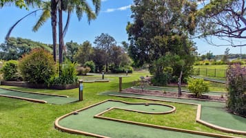 A miniature golf course with multiple holes, surrounded by lush greenery and trees.