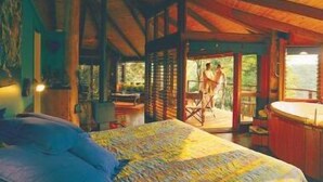 Un dormitorio con una cama grande, techo de madera y vistas a un balcón con dos personas.