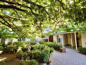 Een binnentuin met een fontein, plantenbakken en een gebouw met een overdekte doorgang.
