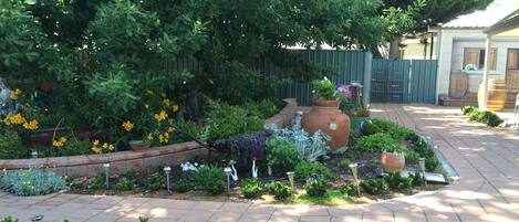 A well-maintained garden with various plants, a large decorative pot, and a statue.
