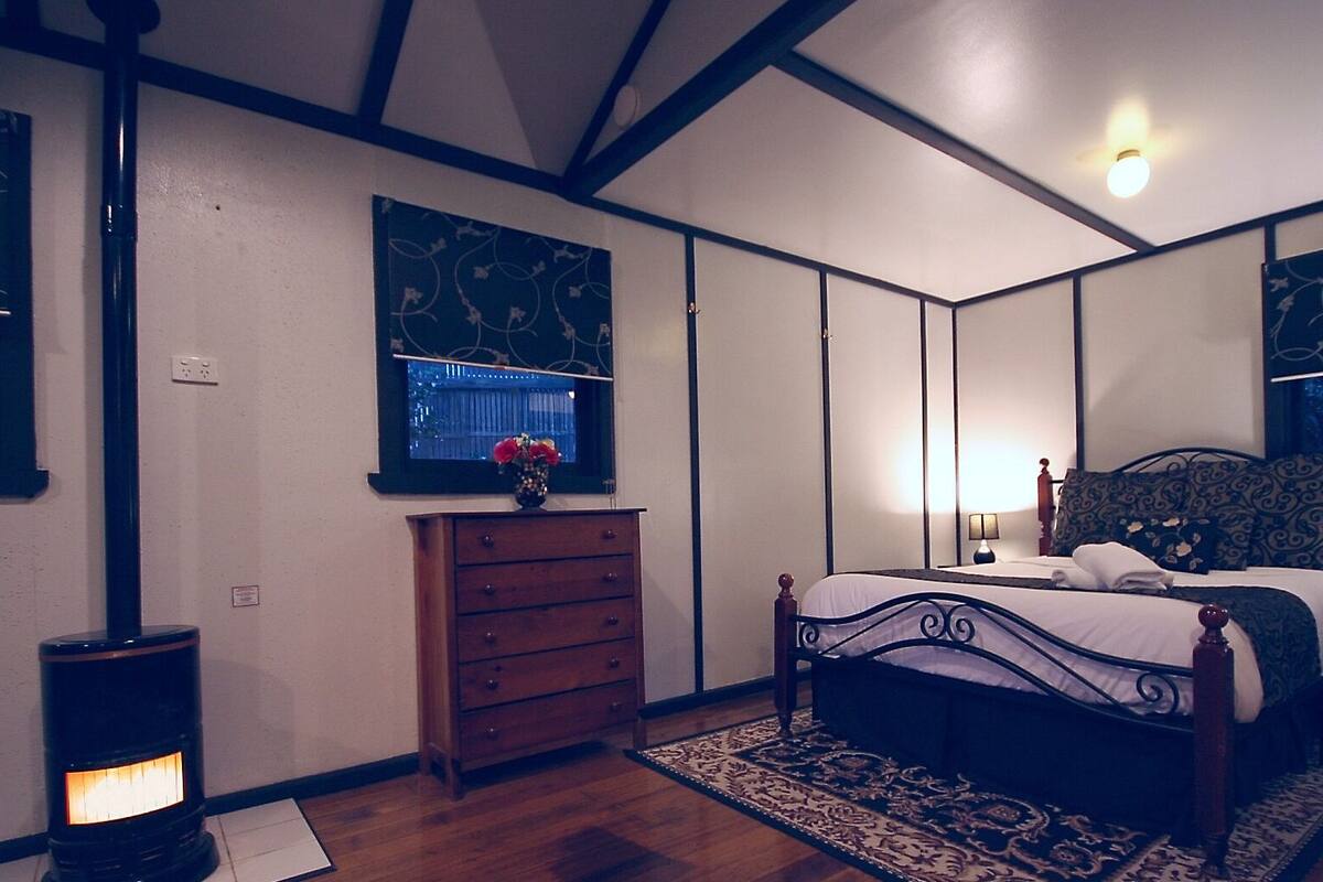 Un dormitorio con cama, cómoda y un calefactor fijado a la pared.