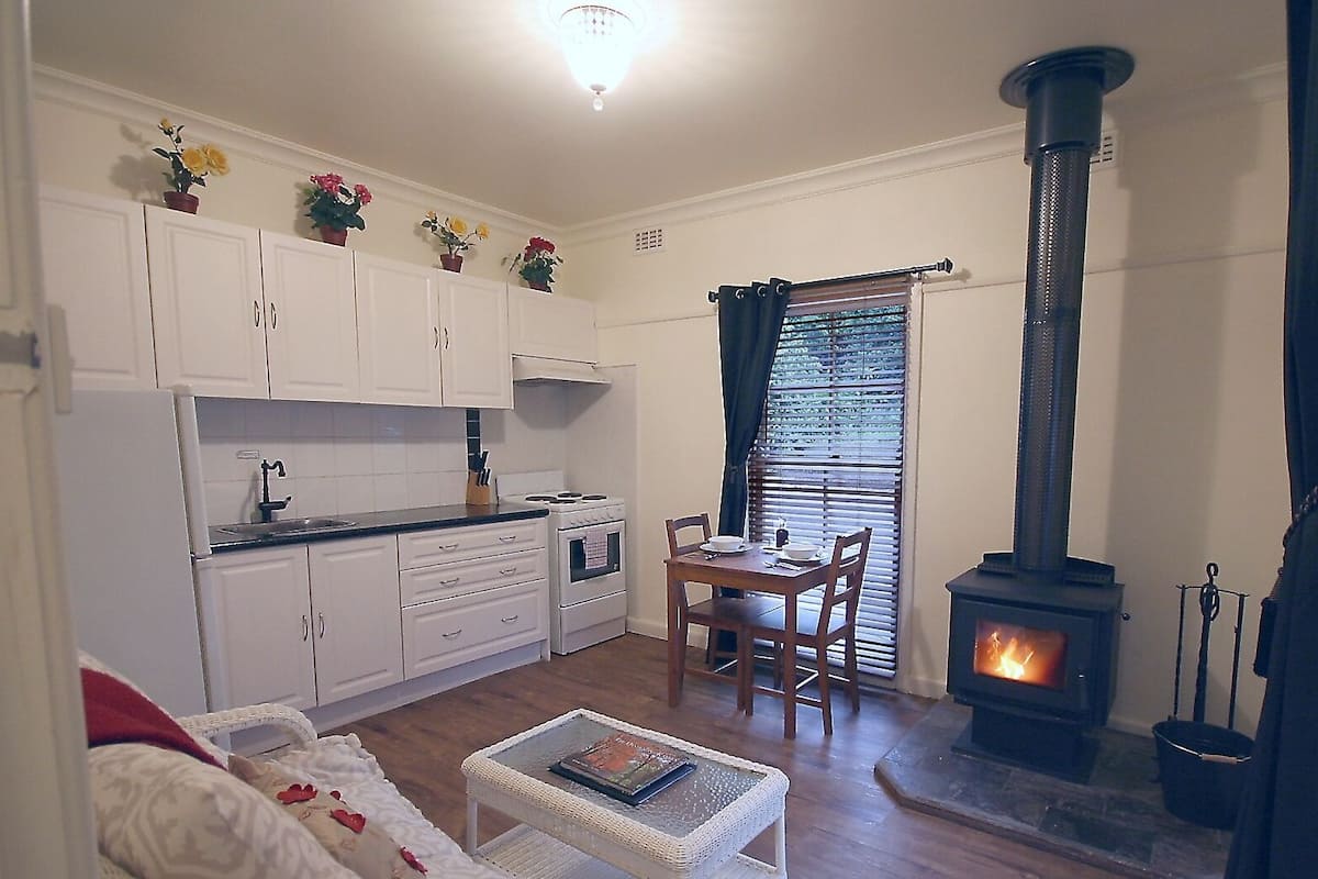 Una sala de estar acogedora con chimenea, un comedor y una cocina con alacenas blancas.