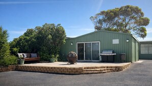Un bâtiment écologique doté d’un patio, d’un barbecue et d’un grand pot décoratif.