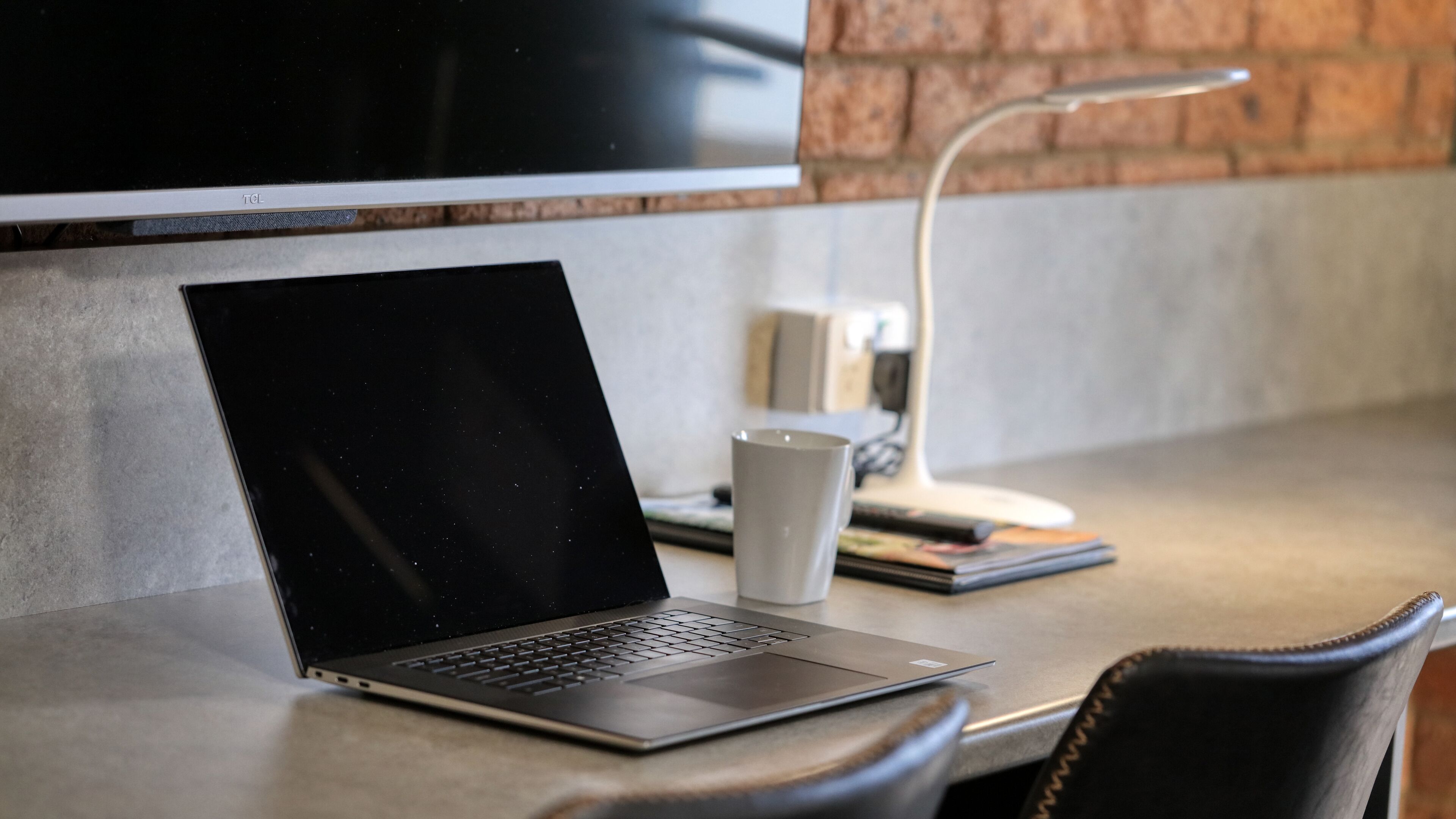 Un ordinateur portable est posé sur une table, à côté d’une tasse et d’un carnet.