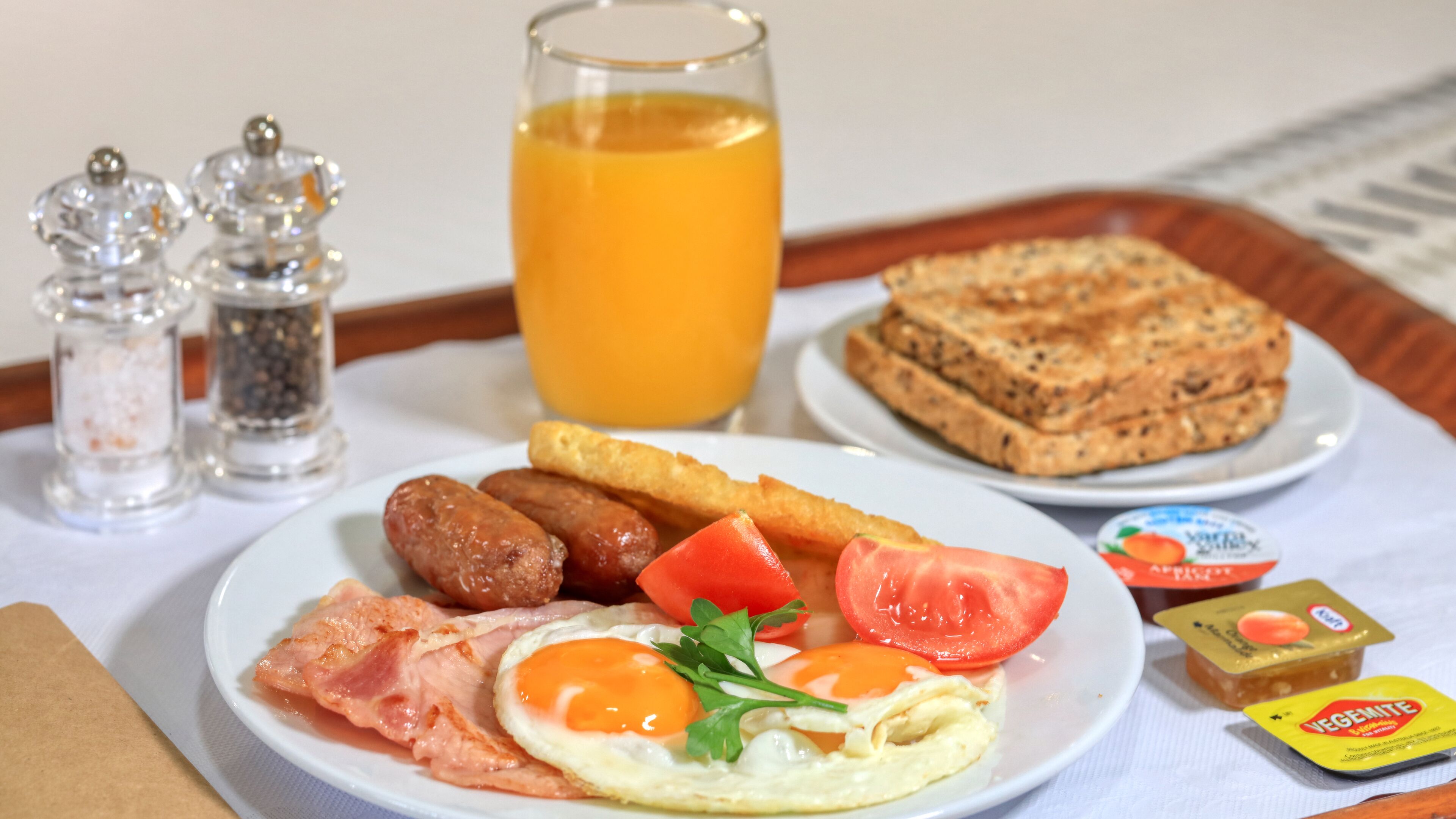 Een ontbijfwagen met toast, worstjes, eieren, tomaten en een glas sinaasappelsap.
