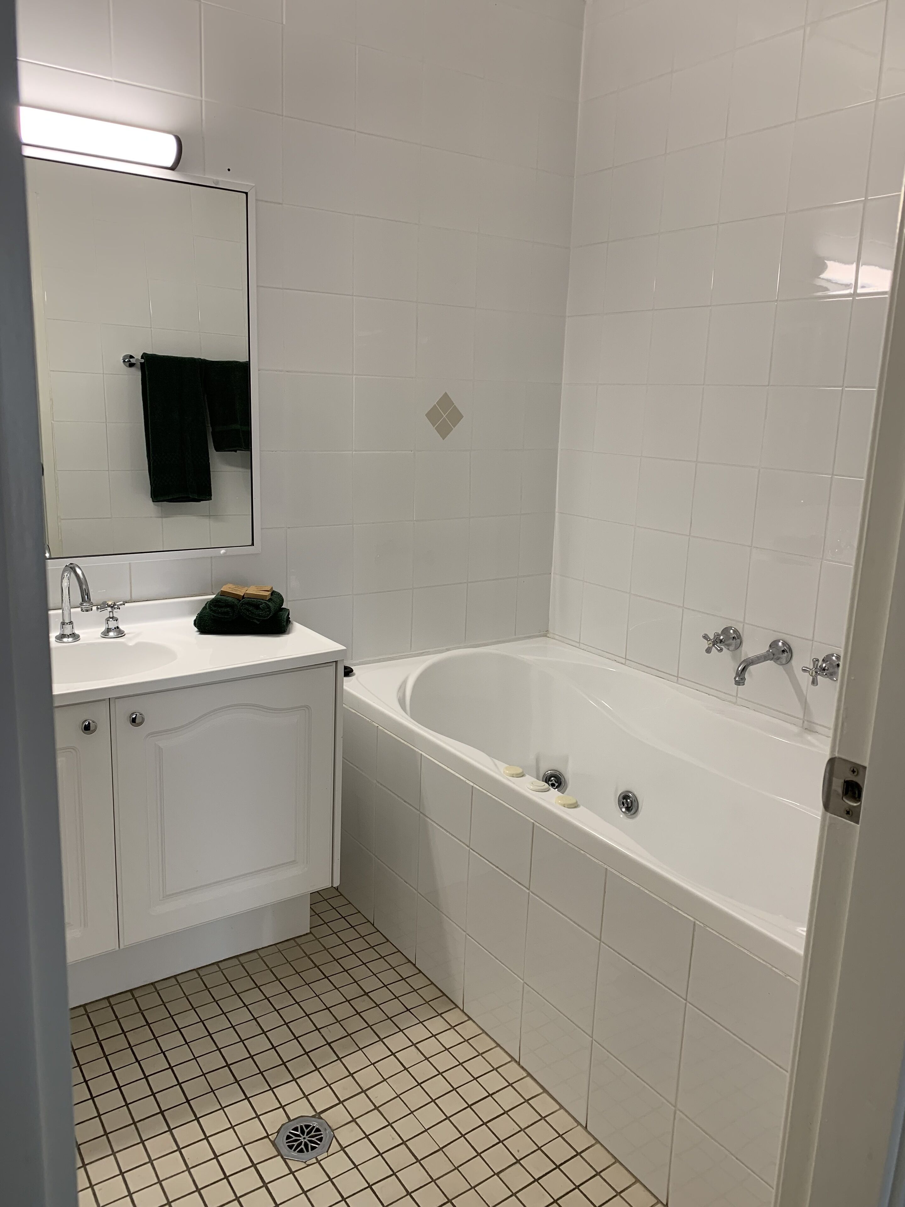 Un baño con lavamanos, espejo y bañera blancos.