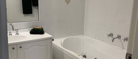 Un baño con lavamanos, espejo y bañera blancos.