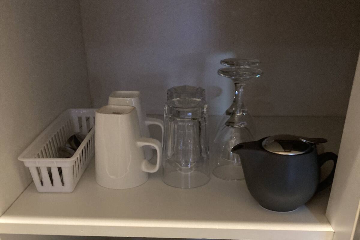 A kitchen with a toaster, kettle, and various glassware on shelves.