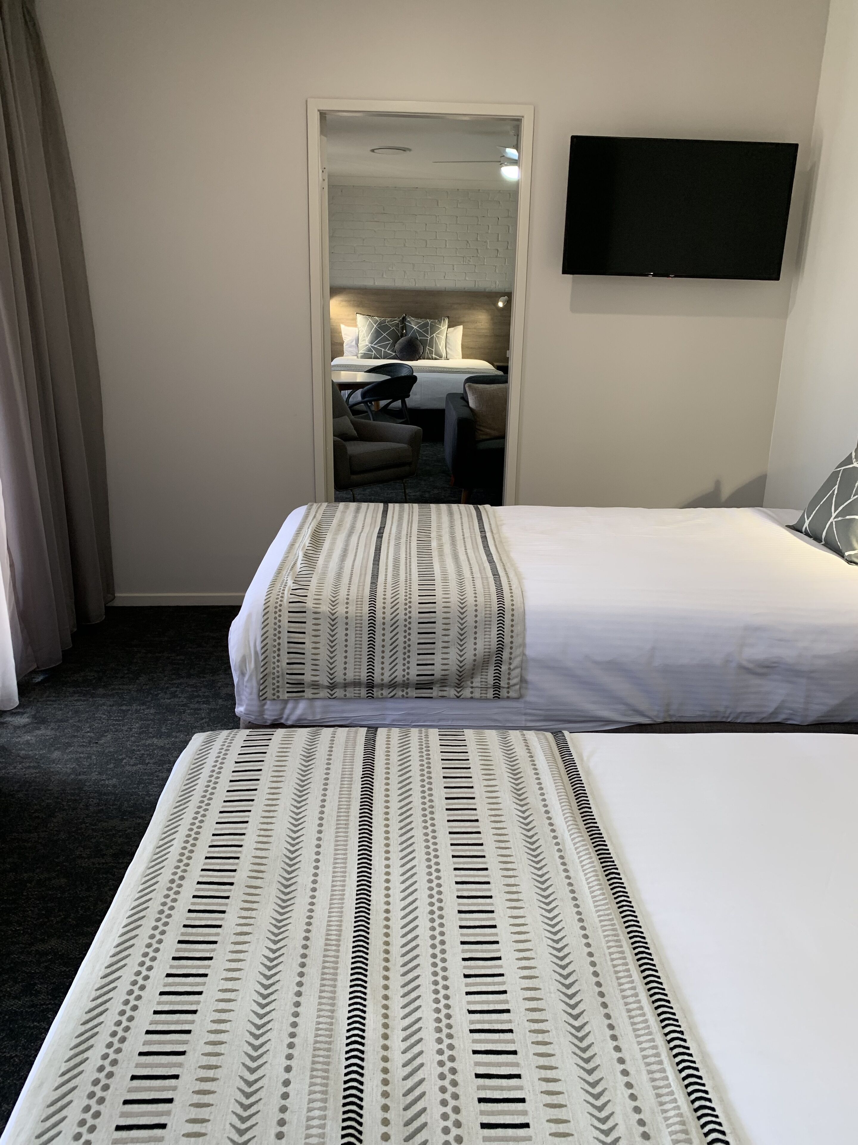 A hotel room with a bed, a chair, a desk, and a television.