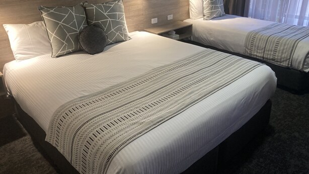 Habitación de hotel con dos camas, cada una con ropa de cama y almohadas estampadas.